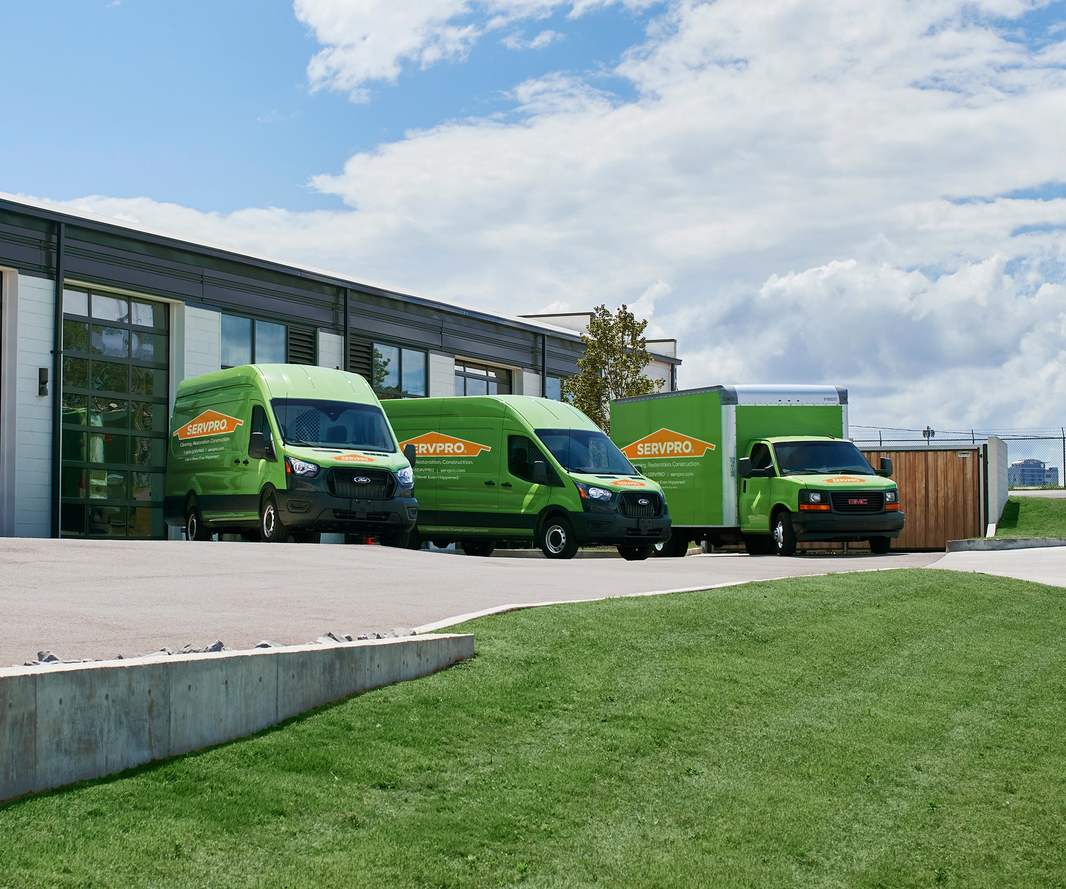 2 SERVPRO vans and a truck parked by building