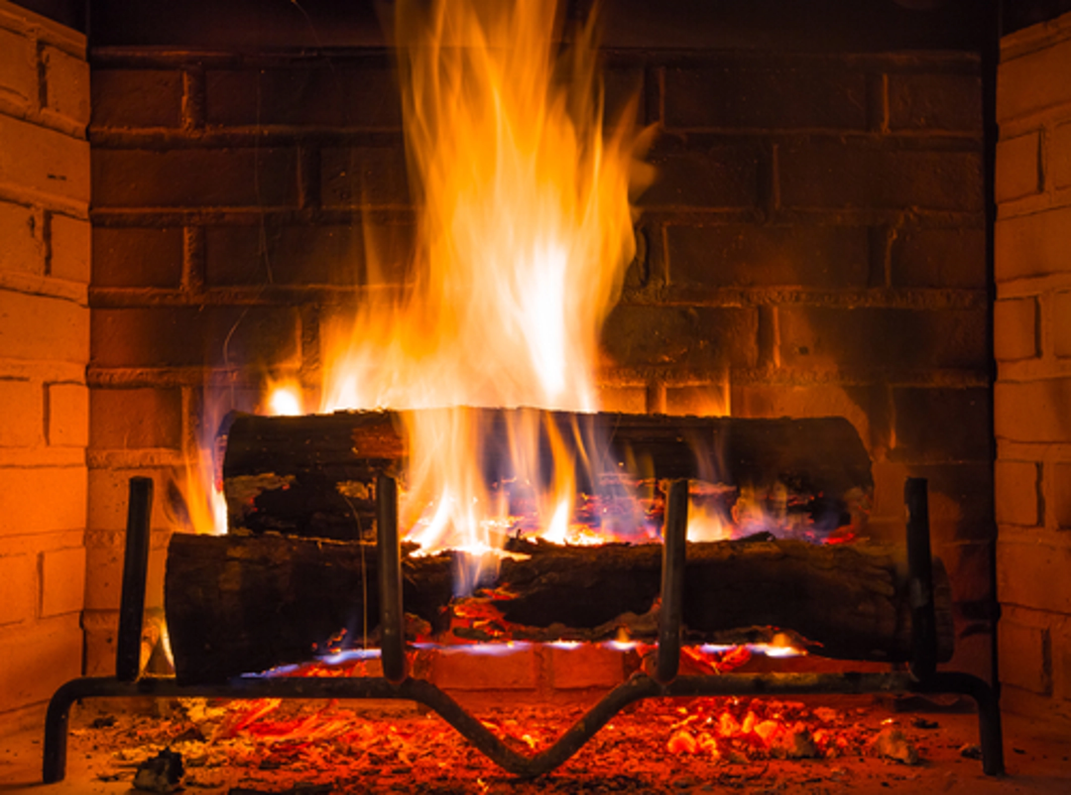 Logs surrounded by flames inside of dark fireplace